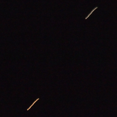 [The sky is dark except for what looks like two falling stars. Mars in the lower left is a thick yellow-orange strip of light. Saturn in the upper right is a thinner white line.]